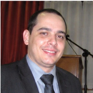 depoimento_5 Um homem de aparência austera, com cabelo longo e barba, se destaca em primeiro plano, expressando-se com intensidade enquanto aponta para a audiência à sua frente. Atrás dele, uma multidão de ouvintes, todos vestidos de forma simples e rústica, observa atentamente suas palavras. O cenário árido, repleto de colinas desérticas, reforça a atmosfera de um chamado urgente à reflexão e mudança. Esse cenário evoca a figura bíblica de João Batista, que prega no deserto e convoca as pessoas a se prepararem para um novo caminho.