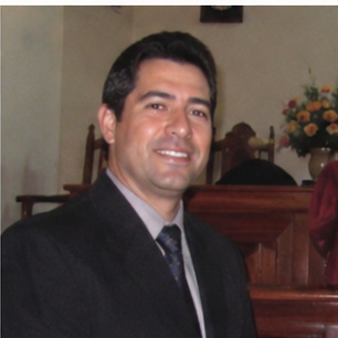depoimento_7 Um homem de aparência austera, com cabelo longo e barba, se destaca em primeiro plano, expressando-se com intensidade enquanto aponta para a audiência à sua frente. Atrás dele, uma multidão de ouvintes, todos vestidos de forma simples e rústica, observa atentamente suas palavras. O cenário árido, repleto de colinas desérticas, reforça a atmosfera de um chamado urgente à reflexão e mudança. Esse cenário evoca a figura bíblica de João Batista, que prega no deserto e convoca as pessoas a se prepararem para um novo caminho.